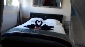 A bed with a heart-shaped decoration on the pillows and a blanket with a blue and white pattern. - chez moumie (La Grande-Béroche)
