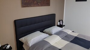 A neatly made bed with a checkered bedspread and pillows, a bedside table with a remote control, and a wall art piece above the bed. - B&B In Centro 33 Home (Salerno)