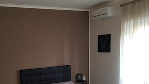 A bedroom with a dark headboard, a bedside table with a clock, and a wall-mounted air conditioner. - B&B In Centro 33 Home (Salerno)