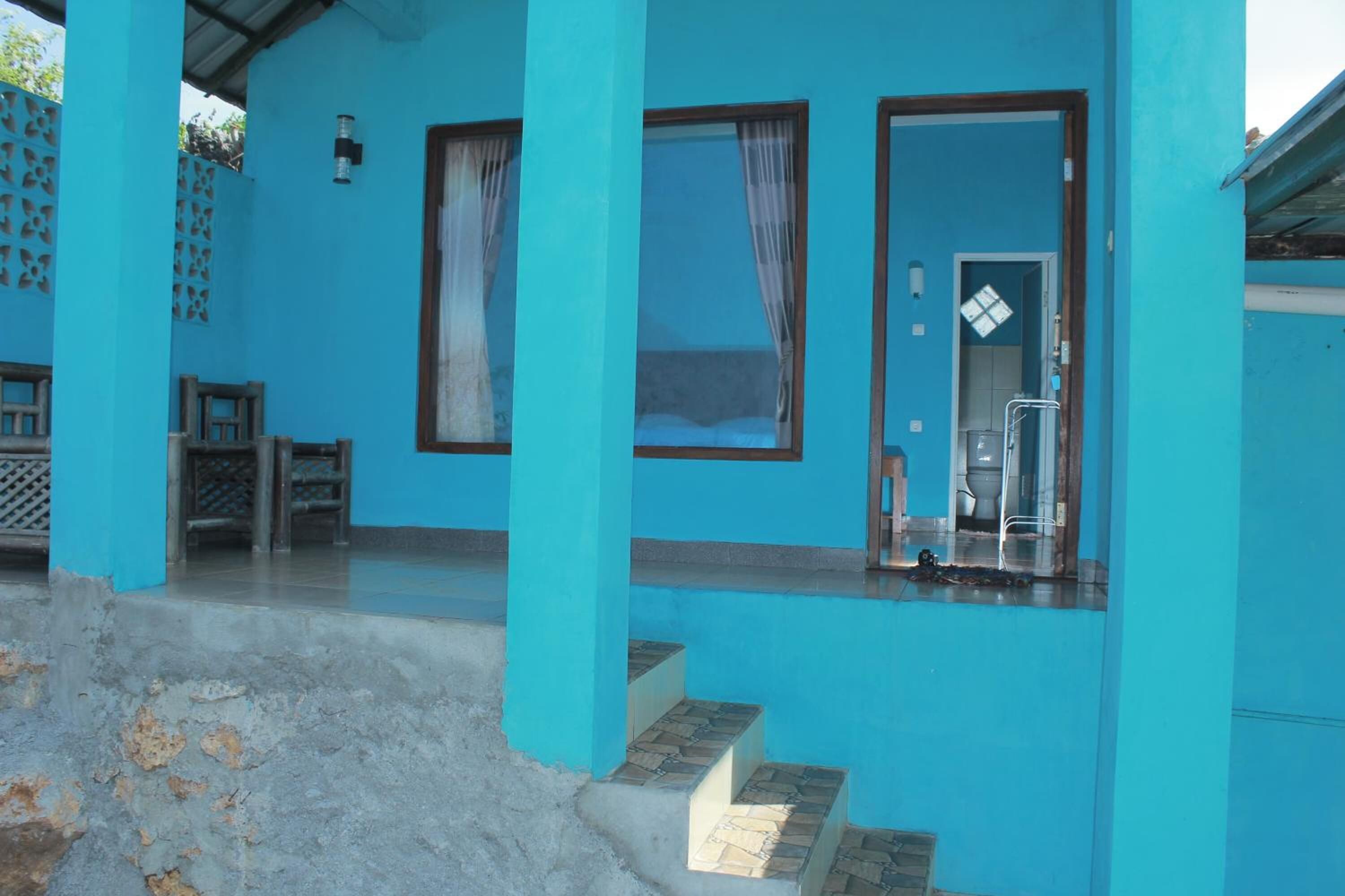 Een blauw gebouw met een trap naar een deur, een klein terras en een zichtbare badkamer.