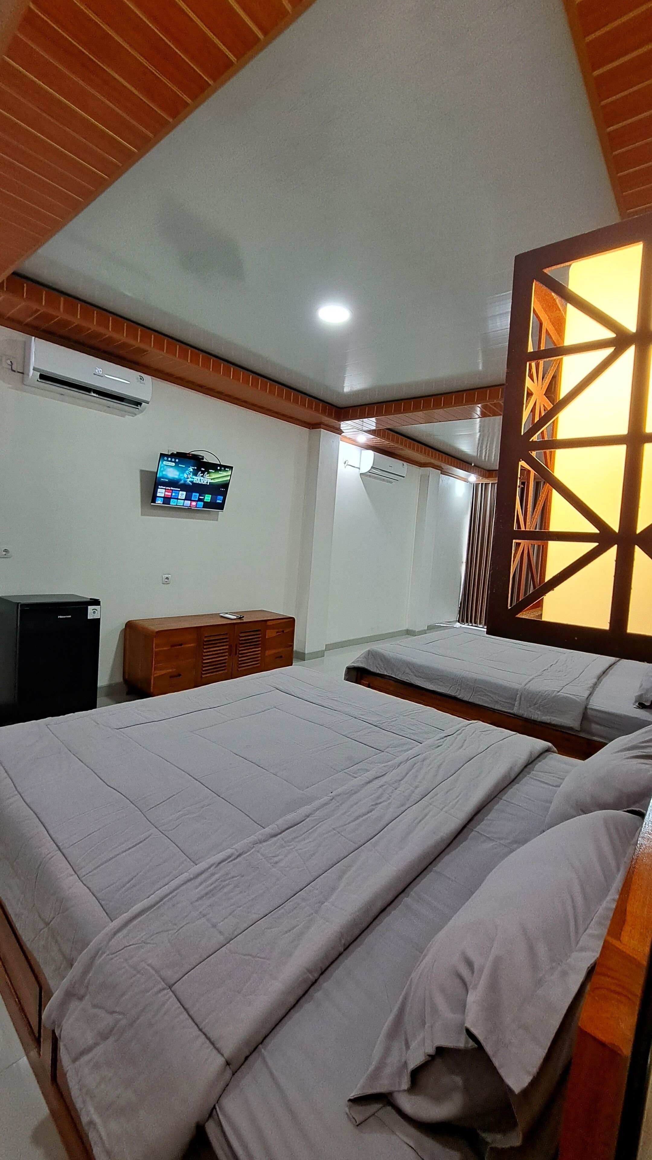 Een hotelkamer met twee bedden, een televisie en een houten scheidingswand.