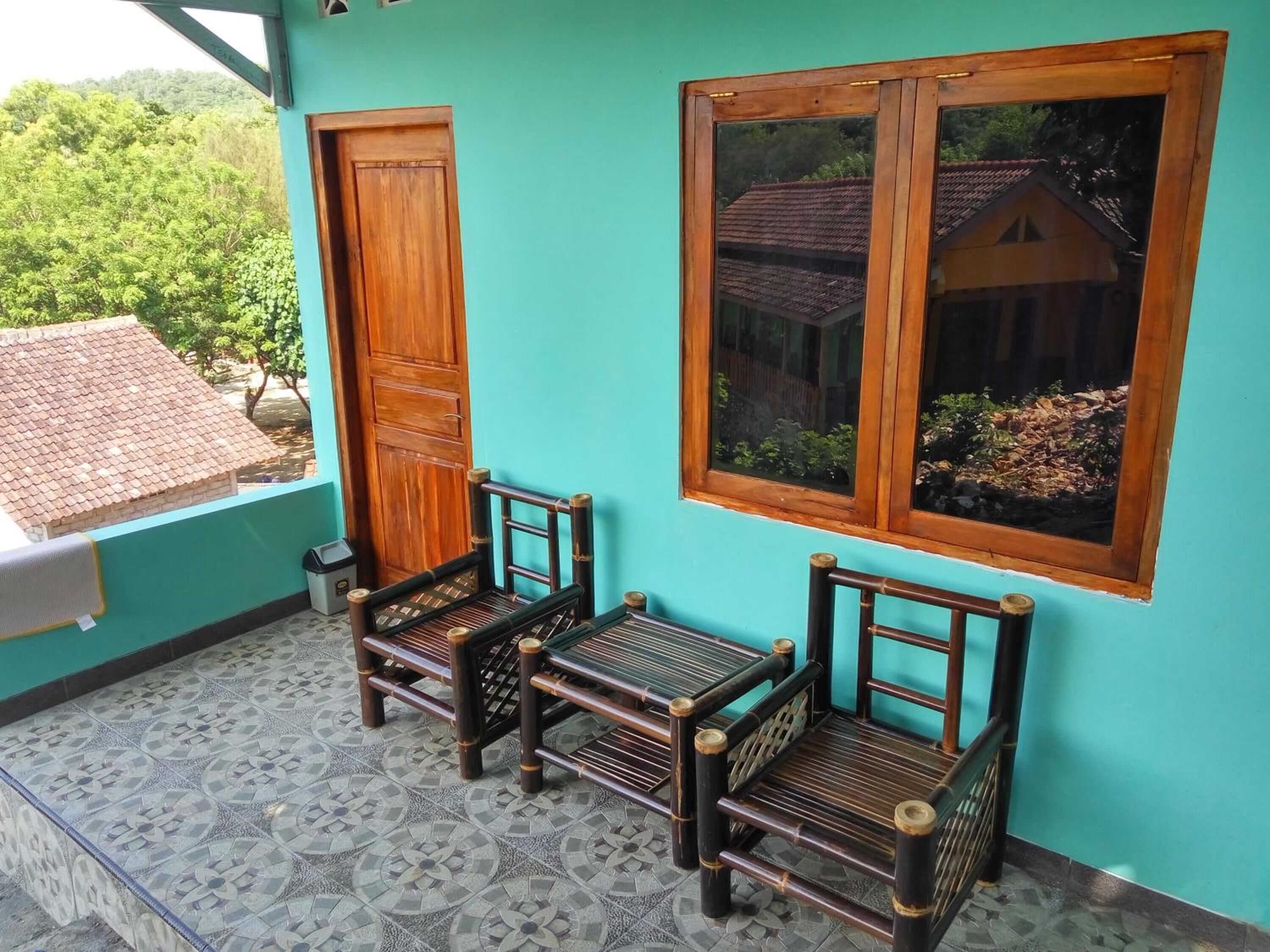 Varanda com duas cadeiras de madeira e janela com vista para uma casa.