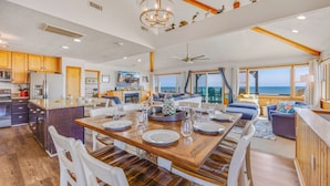 Une cuisine spacieuse, dotée de meubles en bois et d’un coin repas avec une grande table en bois, dressée pour accueillir six personnes.