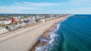 Une ville côtière avec des propriétés donnant sur la plage, une jetée s’avançant dans la mer et un ciel dégagé.
