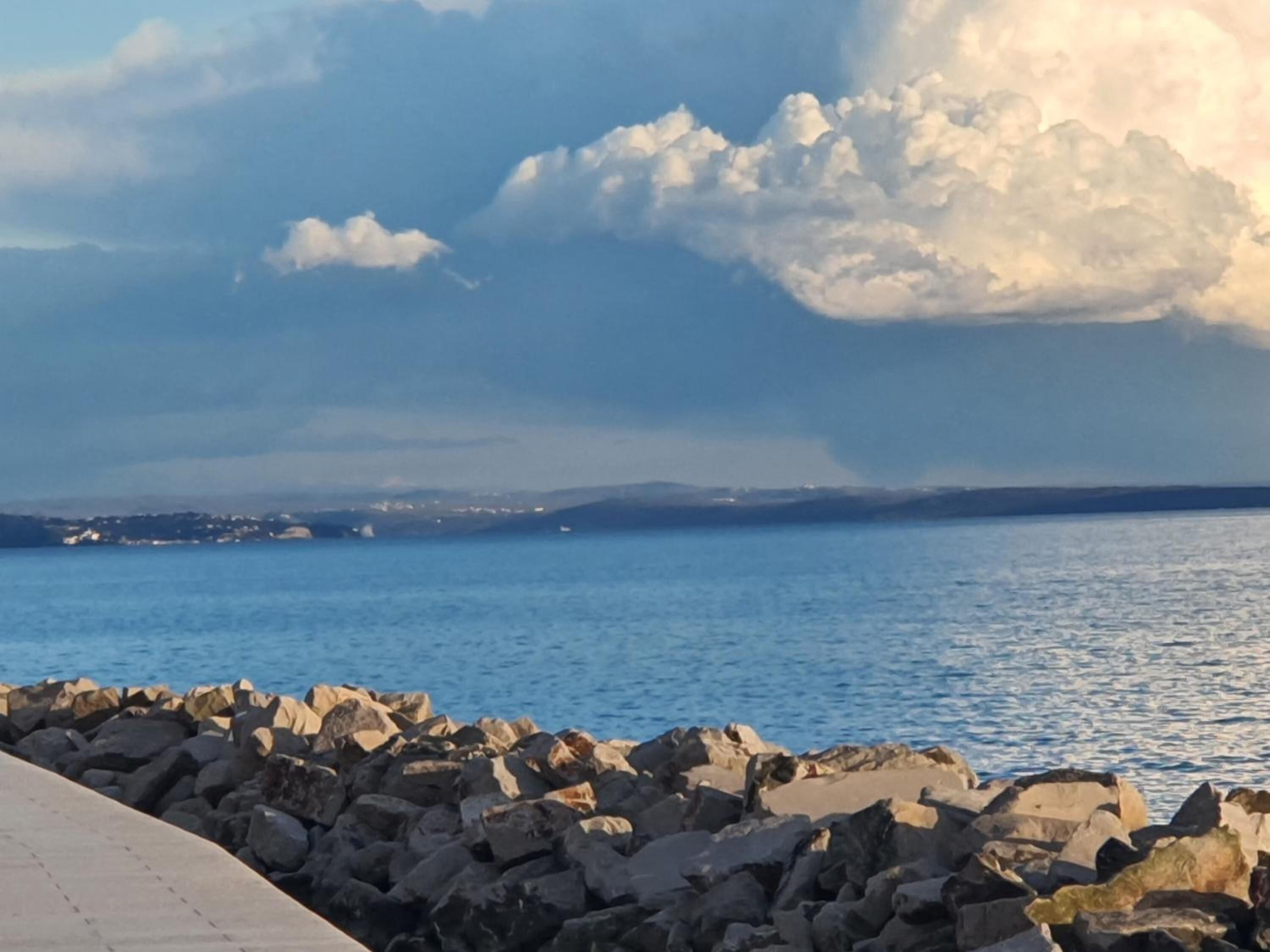 A coastal scene with a rocky shoreline and calm sea.