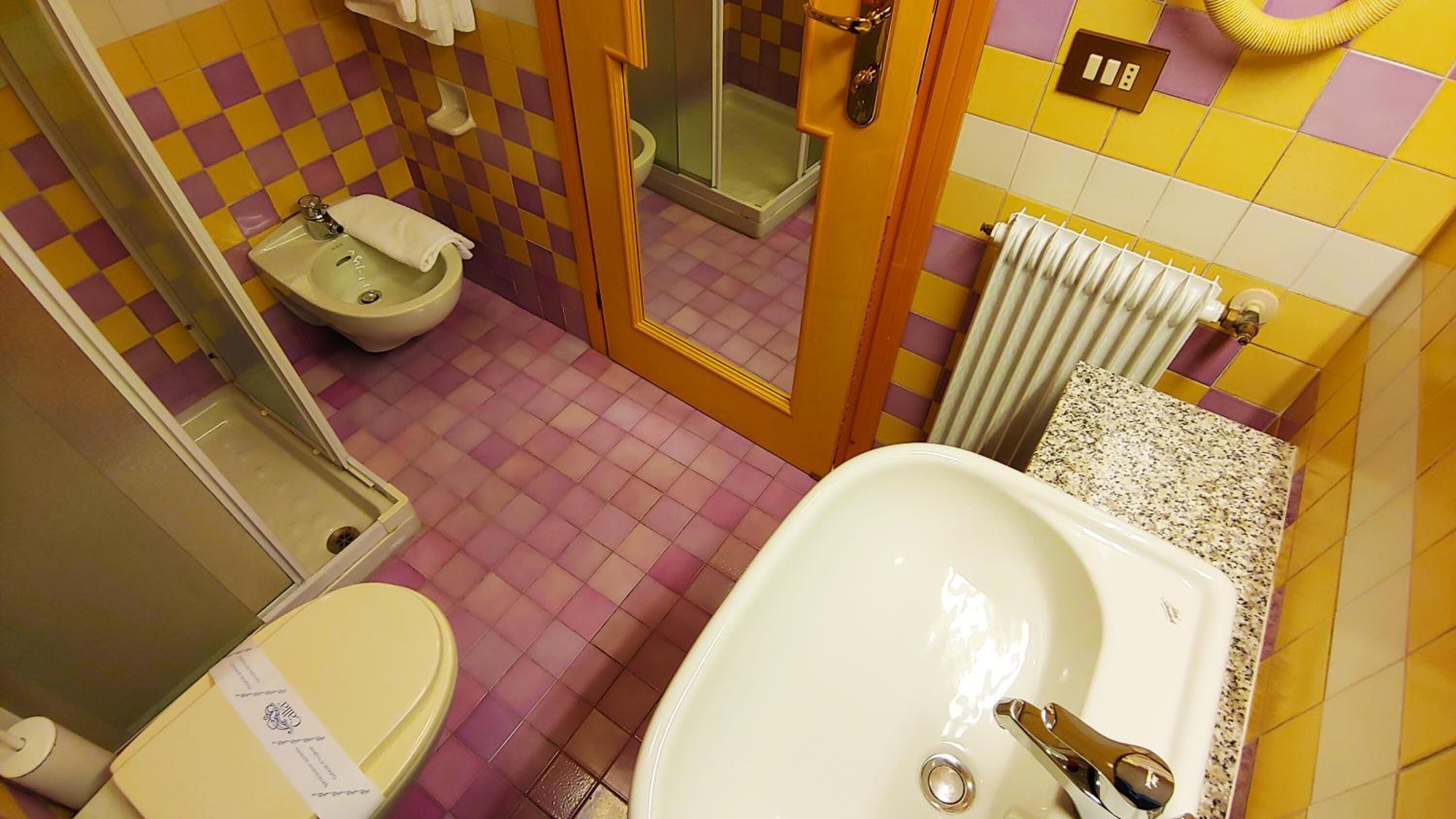A bathroom with a toilet, bidet, sink, and shower.