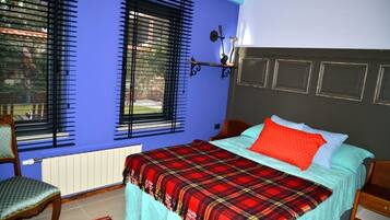 A bedroom with a bed, a chair, a window with blinds, and a radiator.