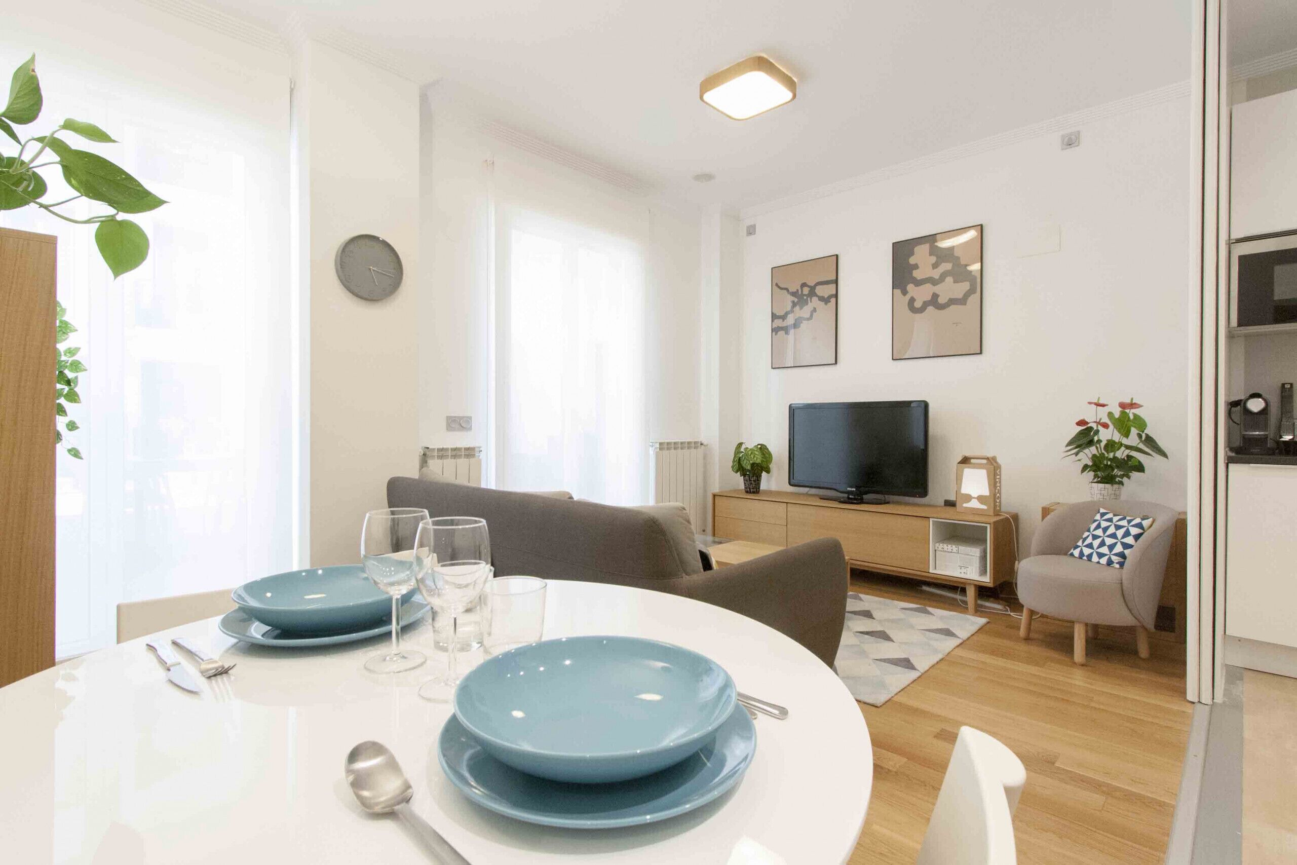 Una sala moderna con comedor, televisor y un espacio de descanso acogedor.