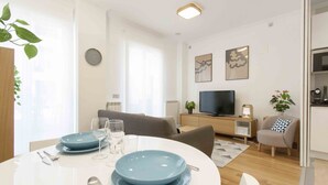 A modern living room with a dining area, a television, and a cozy seating arrangement.