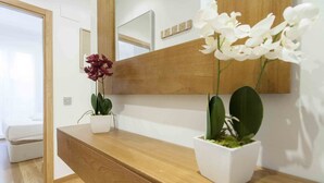 A wooden console table with two potted plants, one with white flowers and another with green leaves.