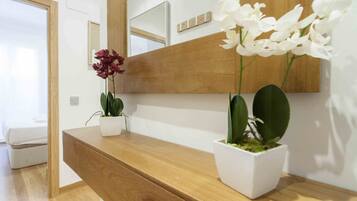 Una consola de madera con dos plantas en macetas, una con flores blancas y otra con hojas verdes.
