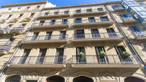 A multi-story building with balconies, arched windows, and a classic architectural style.