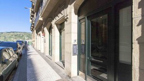 A building with a large glass door, a bicycle parked outside, and a car parked on the sidewalk.