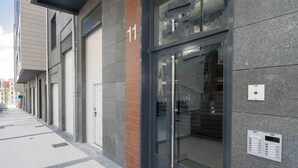 A modern building with a glass entrance, numbered 11, and a keypad on the wall. - Bellagio | The Rentals Collection (San Sebastián)
