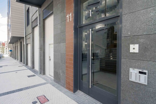 Un bâtiment moderne avec une entrée en verre, portant le numéro 11, et un clavier à code fixé au mur.
