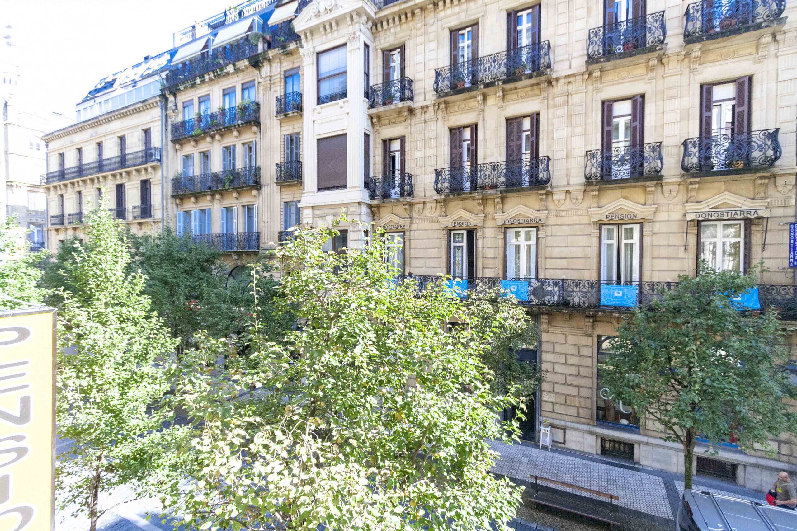 Un edificio de varios pisos con balcones, ventanas y un letrero que indica una pensión.
