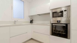 A modern kitchen with white cabinets, a built-in microwave, and an oven.