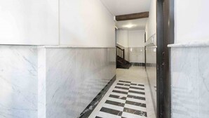 A hallway with white walls, marble flooring, and a checkered pattern.