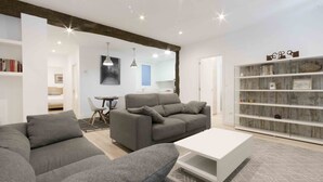 A modern living room with two grey sofas, a white coffee table, and a bookshelf.