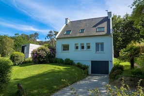 Une maison moderne à deux étages, dotée d’un toit en pente, d’une allée menant à l’entrée et d’une pelouse bien entretenue.