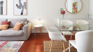 A modern living room with a grey sofa, white chairs, a glass dining table, and artwork on the walls. - Hondarribia | The Rentals Collection (San Sebastián/Donostia)
