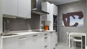 A modern kitchen with white cabinetry, stainless steel appliances, and a view of the sea through a window. - Hondarribia | The Rentals Collection (San Sebastián/Donostia)