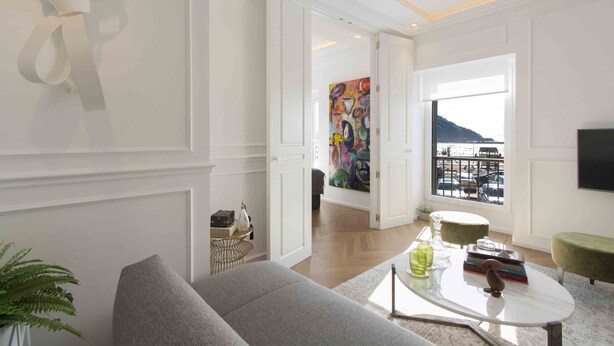 A modern living room with a grey sofa, a coffee table, and a painting on the wall.