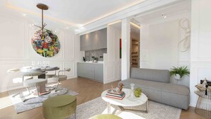 A modern living room with a grey sofa, a round coffee table, and a dining area with a round table and chairs.