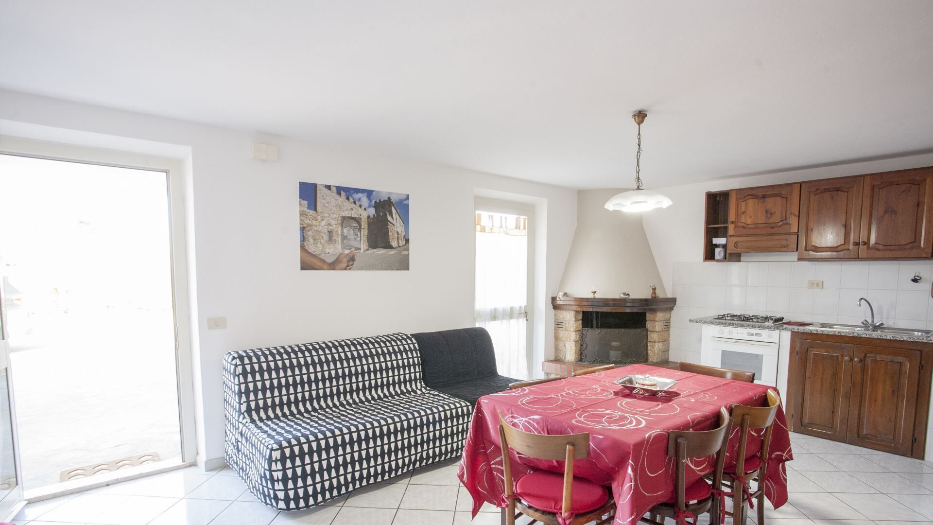 A compact living space with a dining area, a sofa, a fireplace, and a kitchen with wooden cabinets.