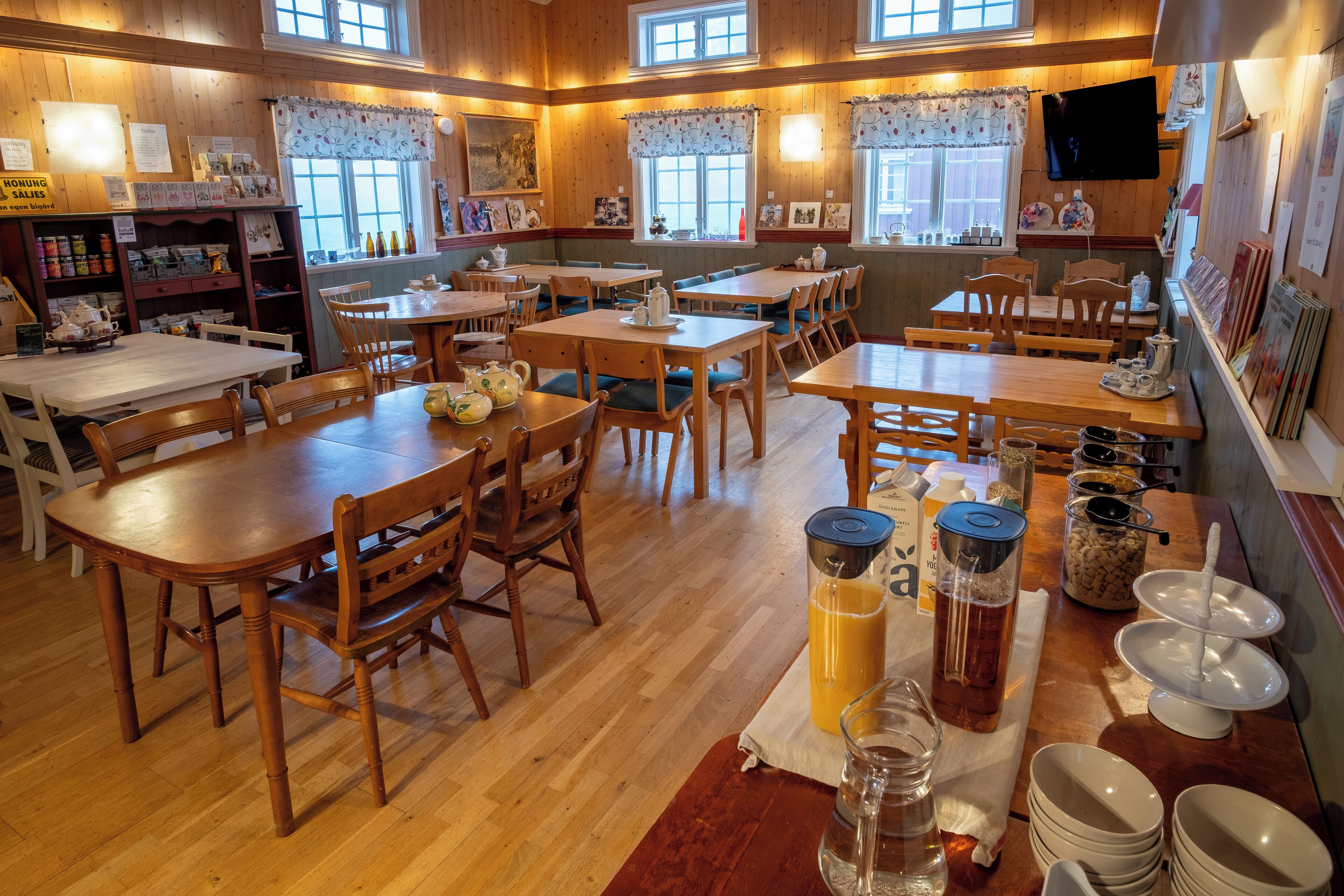 Een gezellig restaurant met houten tafels en stoelen, een koffiehoek en een televisie aan de muur.