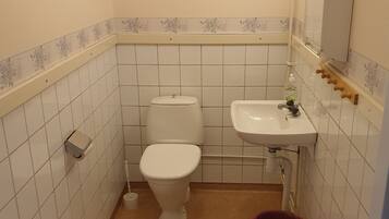 Un baño pequeño con inodoro, lavamanos y un cubo de basura.