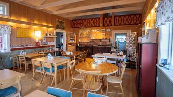 A cozy restaurant with wooden interiors, multiple tables and chairs, and a variety of wall decorations.