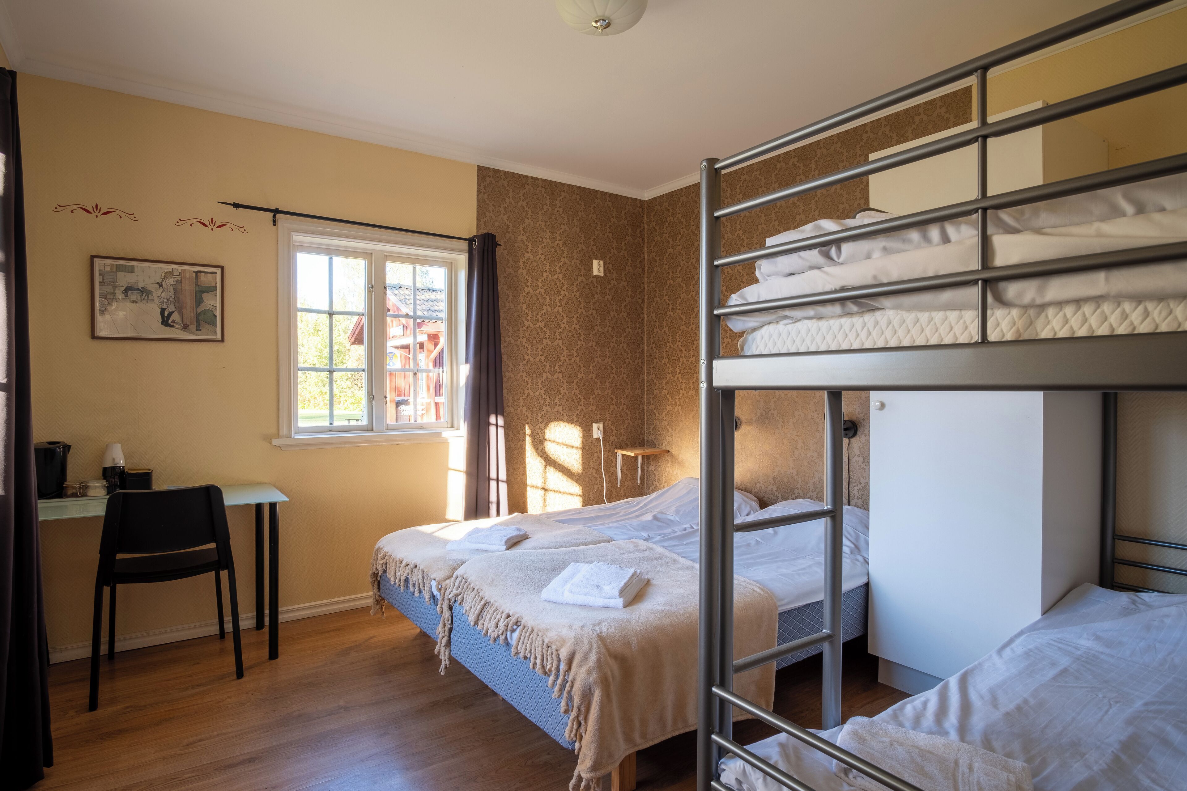 A dormitory room with bunk beds, a desk, and a chair.