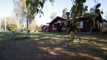 A rustic cabin with a porch and a picnic table in a wooded area.
