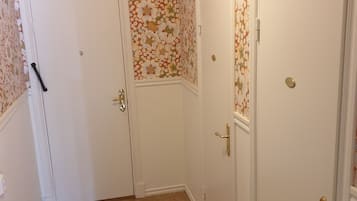 Un couloir avec un papier peint à motifs, des portes blanches et un sol carrelé.