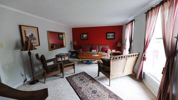 A living room with a red accent wall, a sofa, a coffee table, and wicker furniture.