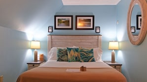 Een slaapkamer met een bed, twee nachtkastjes, een spiegel en twee ingelijste foto’s aan de muur.
