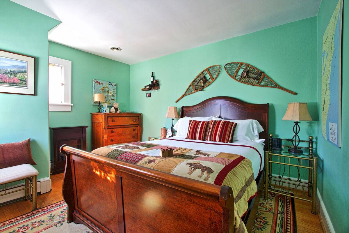 A bedroom with a wooden bed, a dresser, a chair, and a nightstand with a lamp.