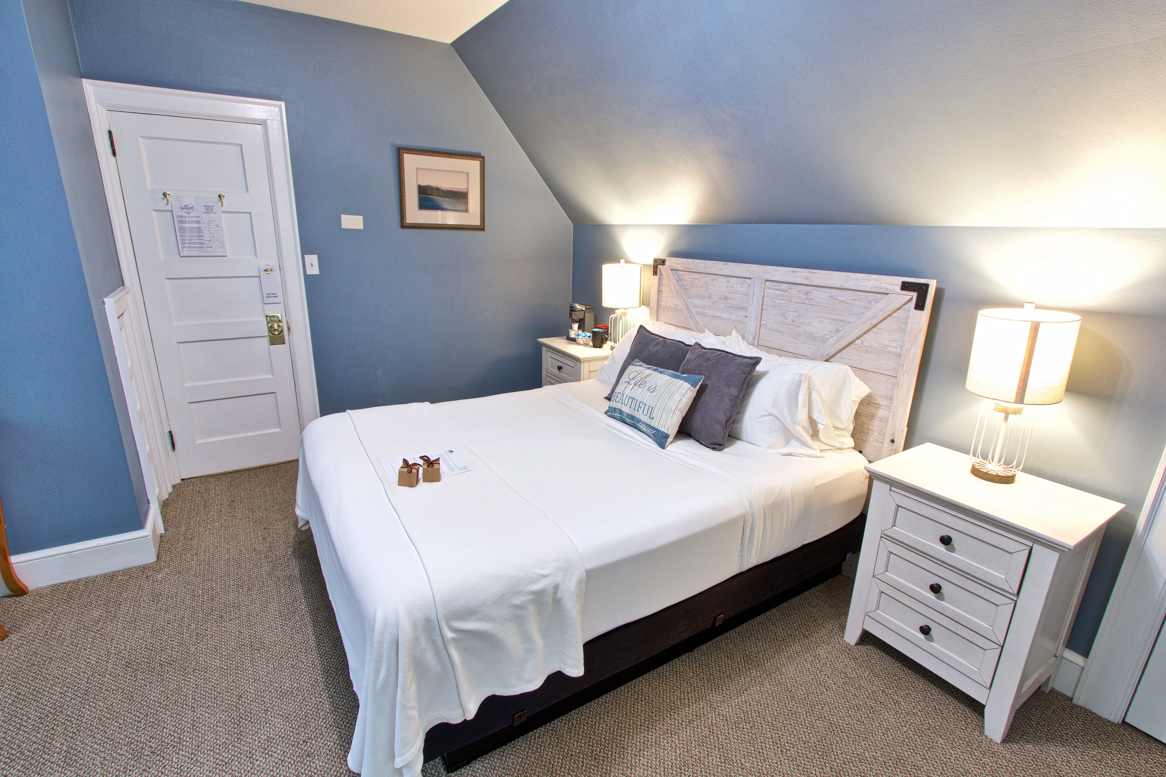 Une chambre à coucher avec un lit, des tables de chevet et une porte.