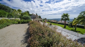 Una casa in pietra con giardino, un vialetto ghiaioso e vista sul mare.