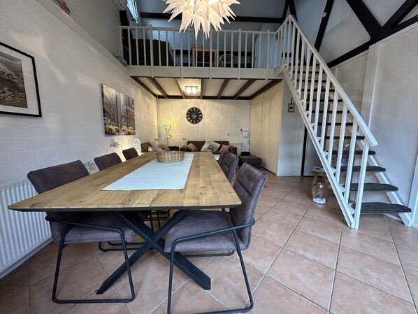 A dining area with a wooden table, chairs, and a white ceiling light.