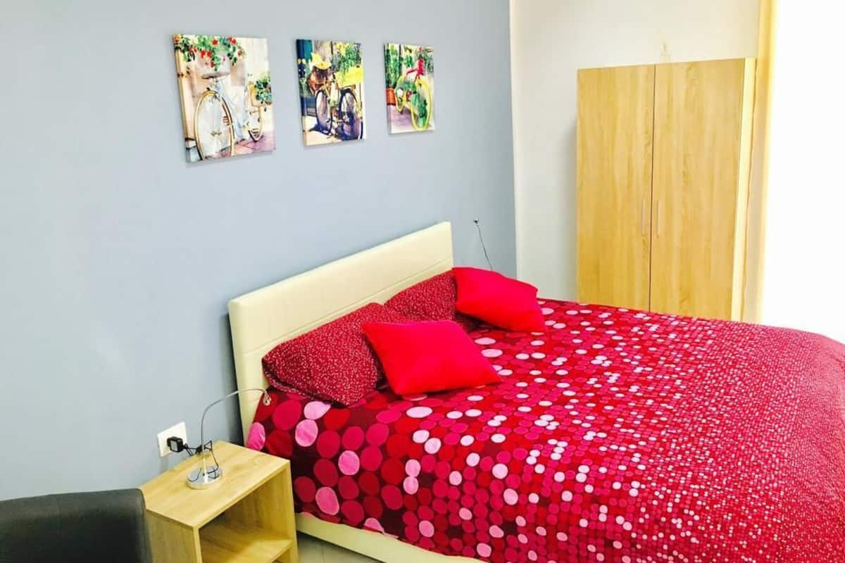 Un dormitorio con una cama, una mesita de noche y tres cuadros colgados en la pared.