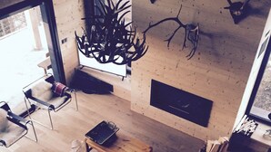 A modern living room with a sofa, a coffee table, and a fireplace. There are antlers on the wall and a chandelier. - Large chalet 12 people (Les Angles)