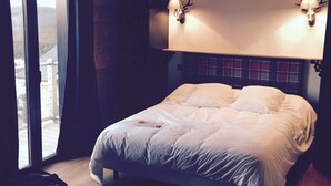 A bedroom with a large bed, a sliding glass door leading to a balcony, and a mounted deer head on the wall. - Large chalet 12 people (Les Angles)