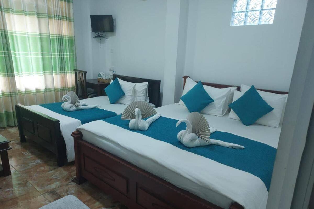 A hotel room with two beds, each with blue bedding and white pillows, and decorative swan pillows.
