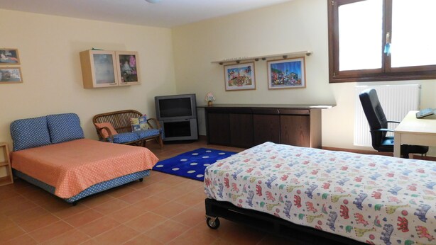 Una habitación con dos camas, un escritorio, una silla, un televisor y obras de arte en las paredes.