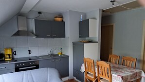 A compact kitchen with grey cabinets, a coffee maker, and a dining table with chairs. - Cozy large vacation apartment, pet friendly, ideal f. Children, (Moorweg)