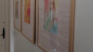 Un couloir orné de trois tableaux abstraits encadrés accrochés au mur.