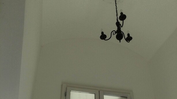 Une pièce avec un plafond blanc, un lustre et une fenêtre donnant sur les montagnes.