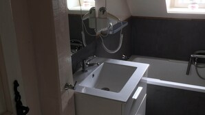 Une salle de bain moderne avec un lavabo blanc, un miroir et une baignoire.